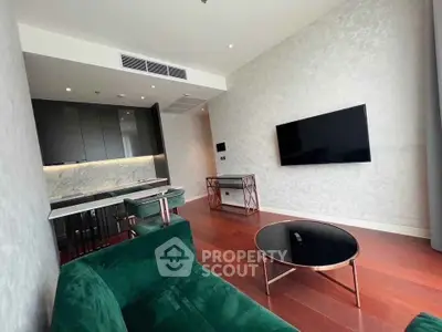 Modern living room with sleek kitchen, green velvet sofa, and wall-mounted TV in luxury apartment.