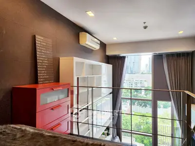 Modern loft with large windows and city view, featuring stylish furniture and ample natural light.