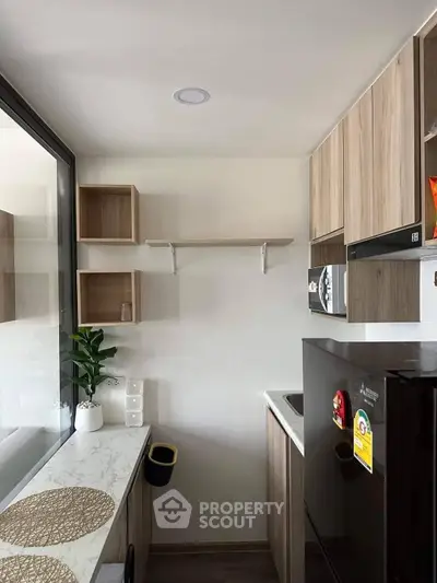 Sleek modern kitchen with wooden cabinetry and marble countertops, featuring built-in microwave and ample storage space, perfect for culinary enthusiasts.