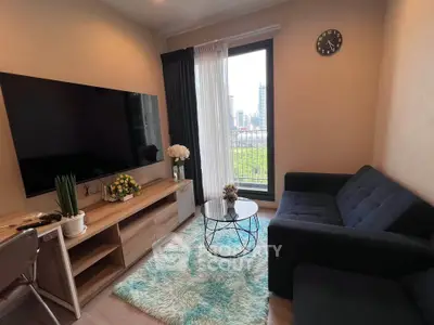 Modern living room with large TV, cozy sofa, and city view balcony in stylish apartment.