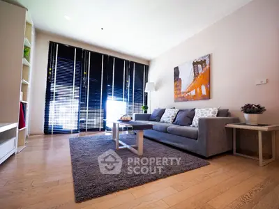 Modern living room with stylish decor, cozy gray sofa, and large windows with blinds.