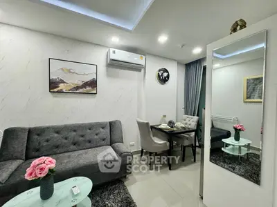 Modern living room with stylish decor, featuring a plush gray sofa, elegant dining area, and contemporary artwork.