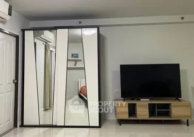 Modern living room with mirrored wardrobe and sleek TV stand, showcasing contemporary interior design.