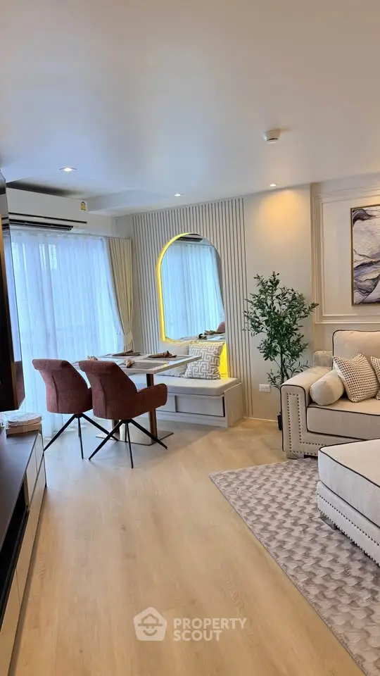 Modern living room with stylish decor and cozy seating area, featuring elegant lighting and natural light from large windows.