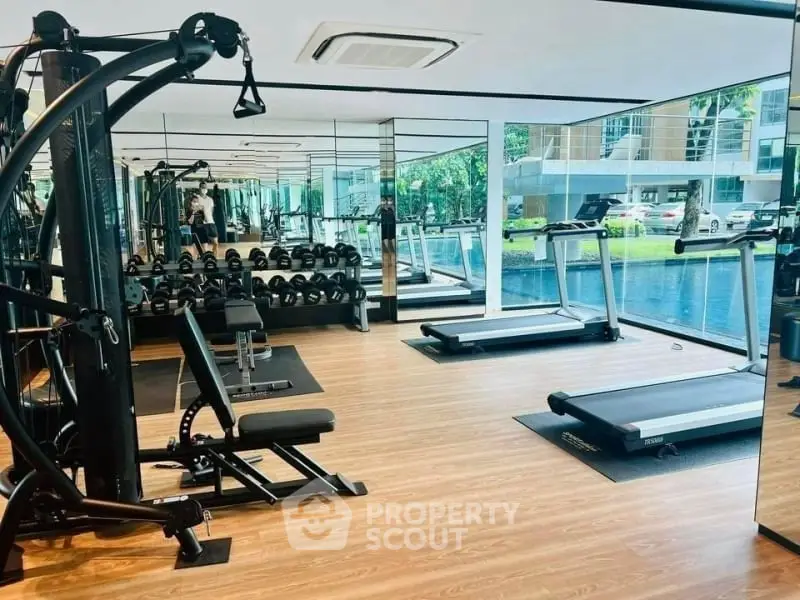 Modern gym with state-of-the-art equipment and pool view in luxury residential complex.