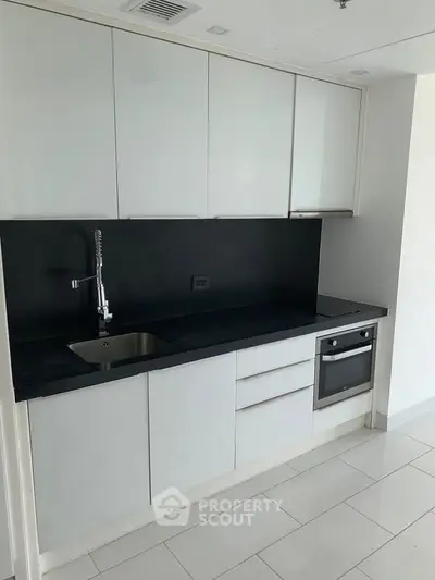 Modern kitchen with sleek cabinetry and built-in oven in a contemporary apartment.