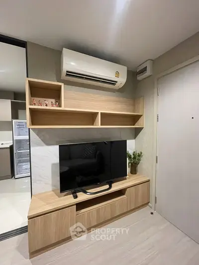 Modern living room with sleek TV setup and air conditioning in stylish apartment.