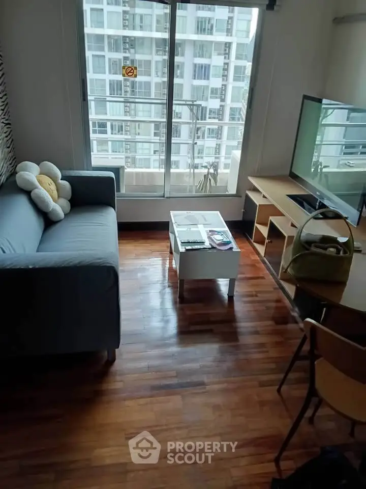 Cozy living room with wooden floors, modern sofa, and large window with city view.