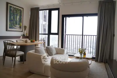 Modern living room with large windows and balcony offering stunning city views.
