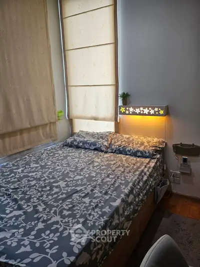 Cozy bedroom with floral bedding and soft lighting, perfect for relaxation.