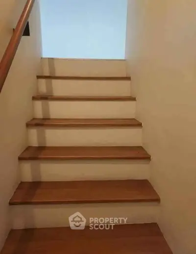 Simple wooden staircase with handrail in a modern home interior