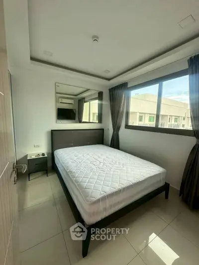 Modern bedroom with large window and minimalist design in urban apartment.