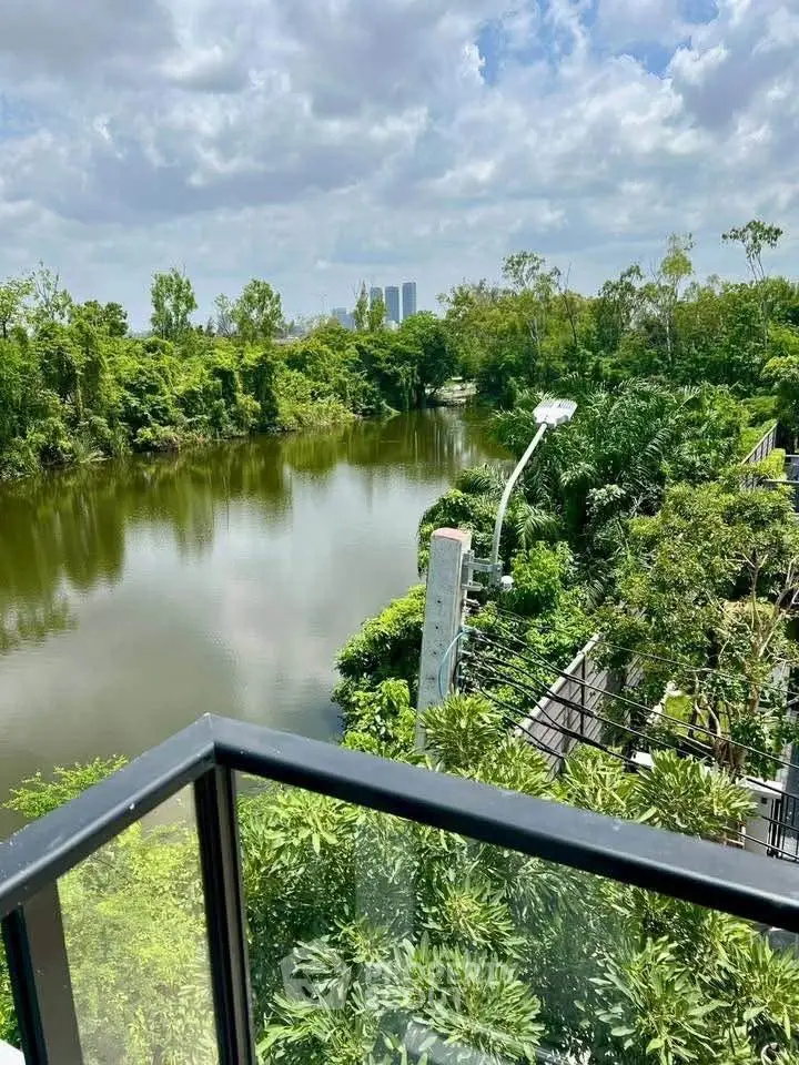 Stunning river view from a modern balcony with lush greenery and city skyline.