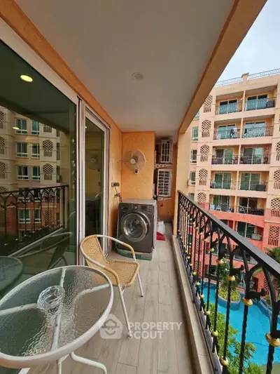 Charming balcony with pool view, featuring outdoor seating and washing machine, perfect for relaxation.