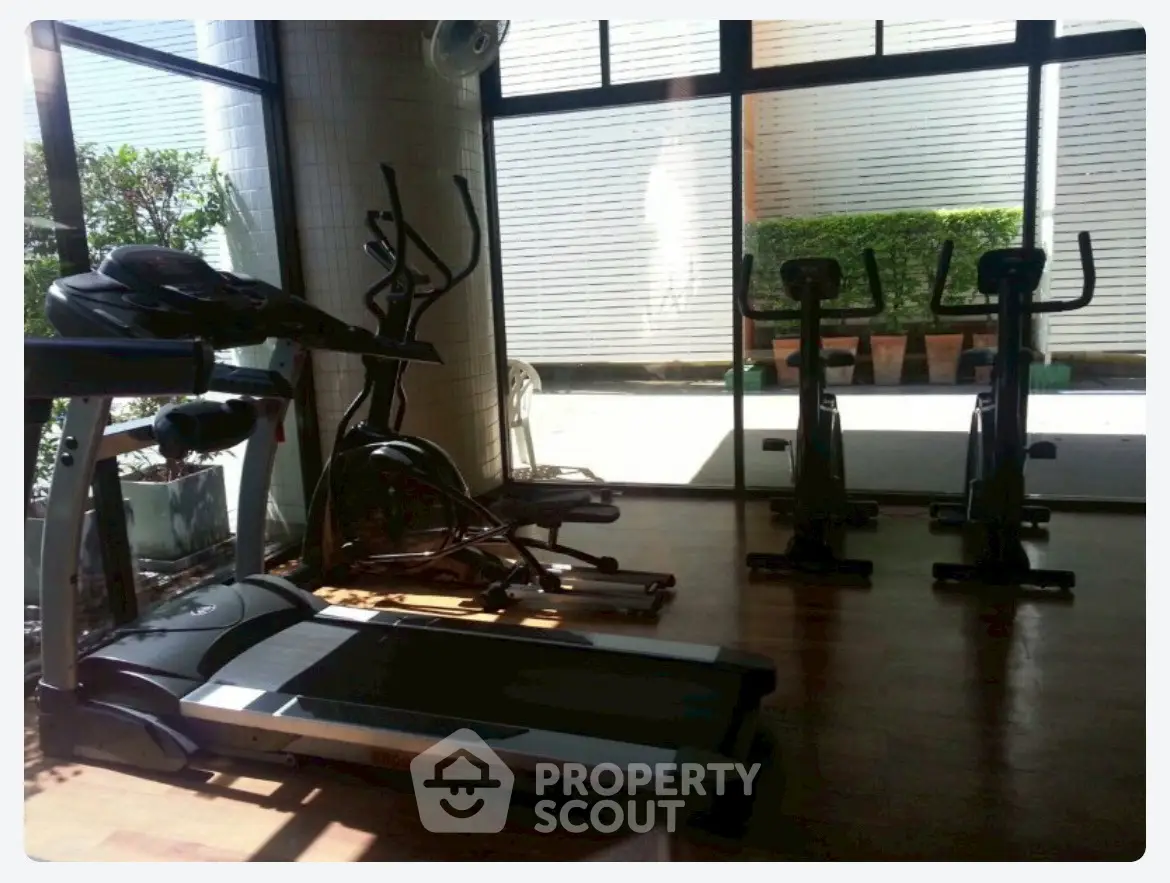 Modern gym with exercise equipment and large windows in a residential building.