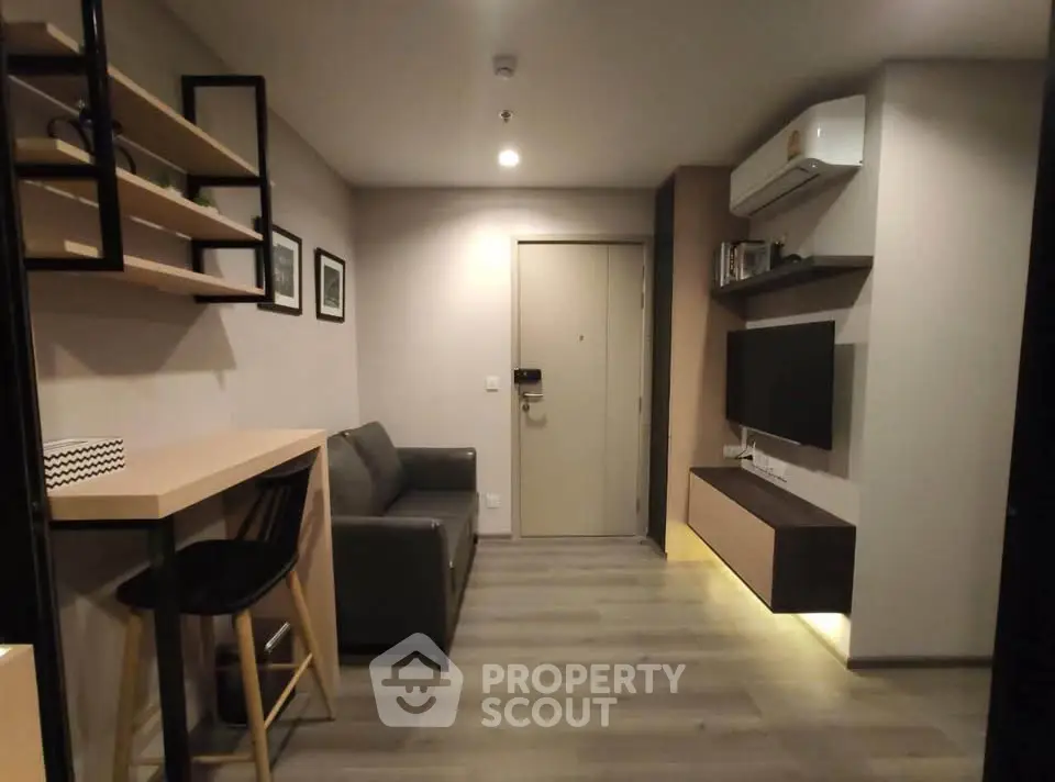 Modern living room with sleek furniture and wall-mounted TV in a cozy apartment.
