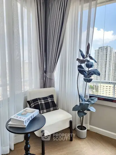 Chic corner with elegant chair, stylish table, and city view, perfect for relaxation or reading.