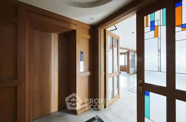Elegant interior with wooden elevator doors and stained glass accents in a modern building.