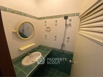 Charming bathroom with green tile accents and modern shower fixtures.