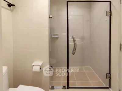 Modern bathroom with glass shower enclosure and tiled walls.