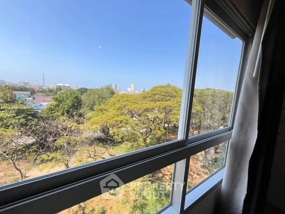 Stunning cityscape view from a modern apartment window, showcasing lush greenery and urban skyline.