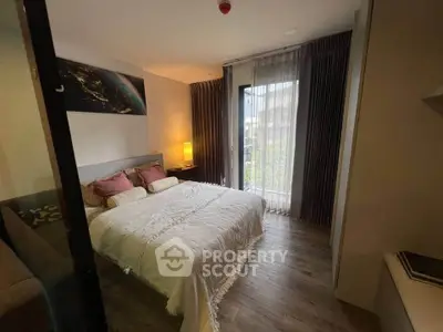 Cozy bedroom with elegant decor and natural light from large window.