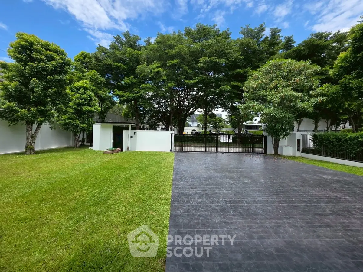 Spacious garden with paved driveway and lush trees in a serene residential area.
