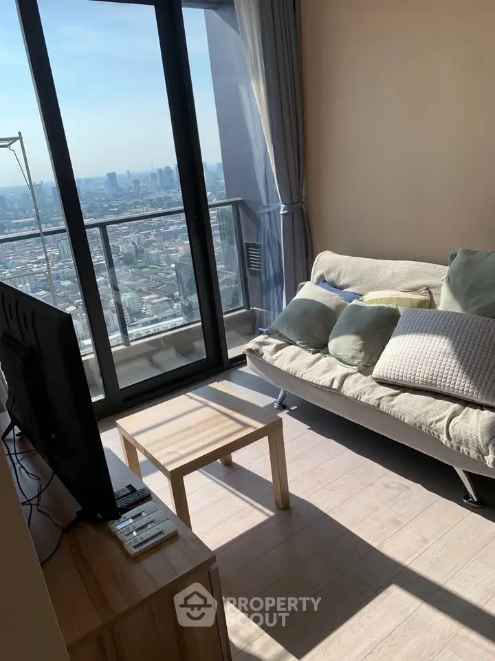 Modern living room with stunning city view from high-rise balcony, featuring cozy sofa and sleek decor.