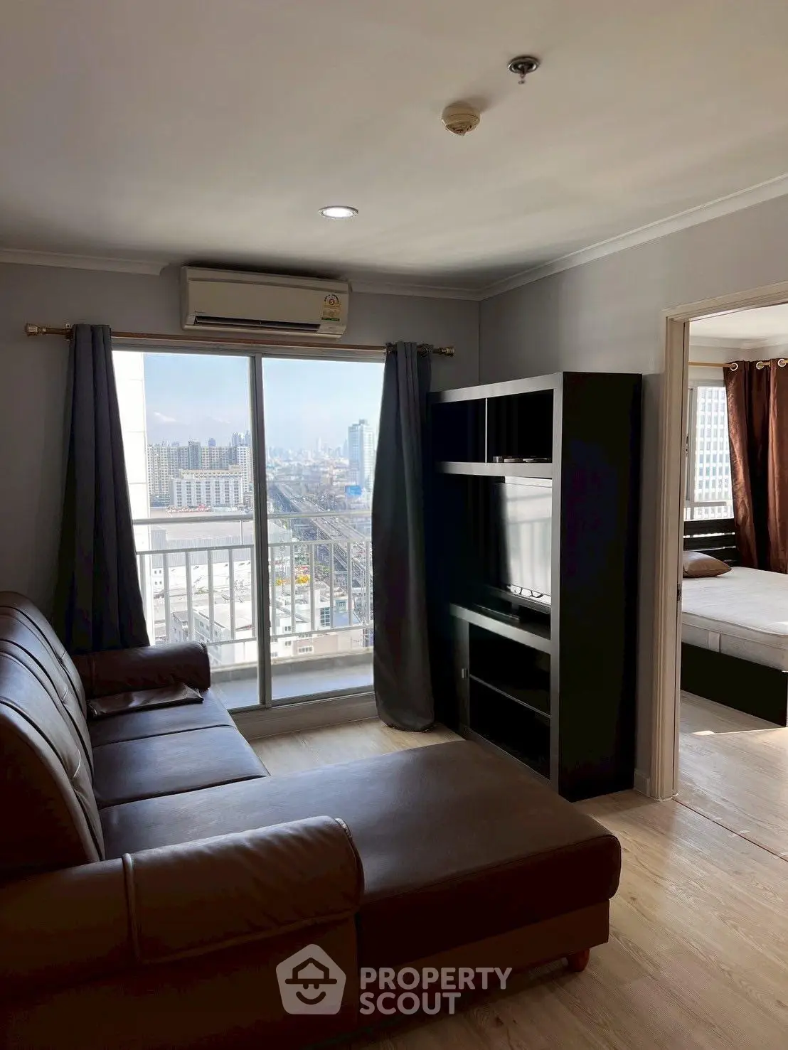 Modern living room with city view, featuring sleek furniture and large windows for natural light.