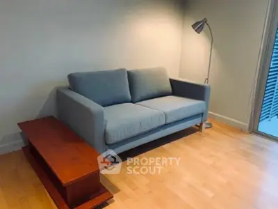 Cozy living room with modern gray sofa and stylish floor lamp on wooden flooring.