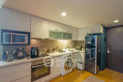 Modern kitchen with sleek appliances and stylish backsplash in a cozy apartment.