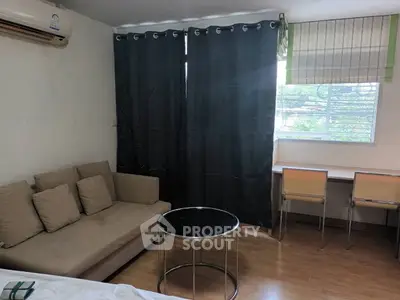 Cozy living room with modern sofa, round coffee table, and window view.