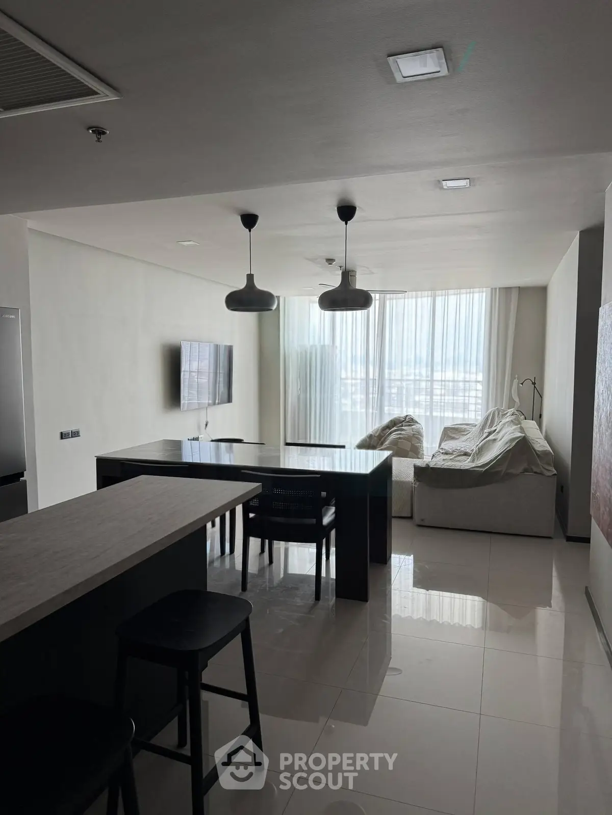 Modern open-layout living room with sleek furniture and large windows offering natural light.