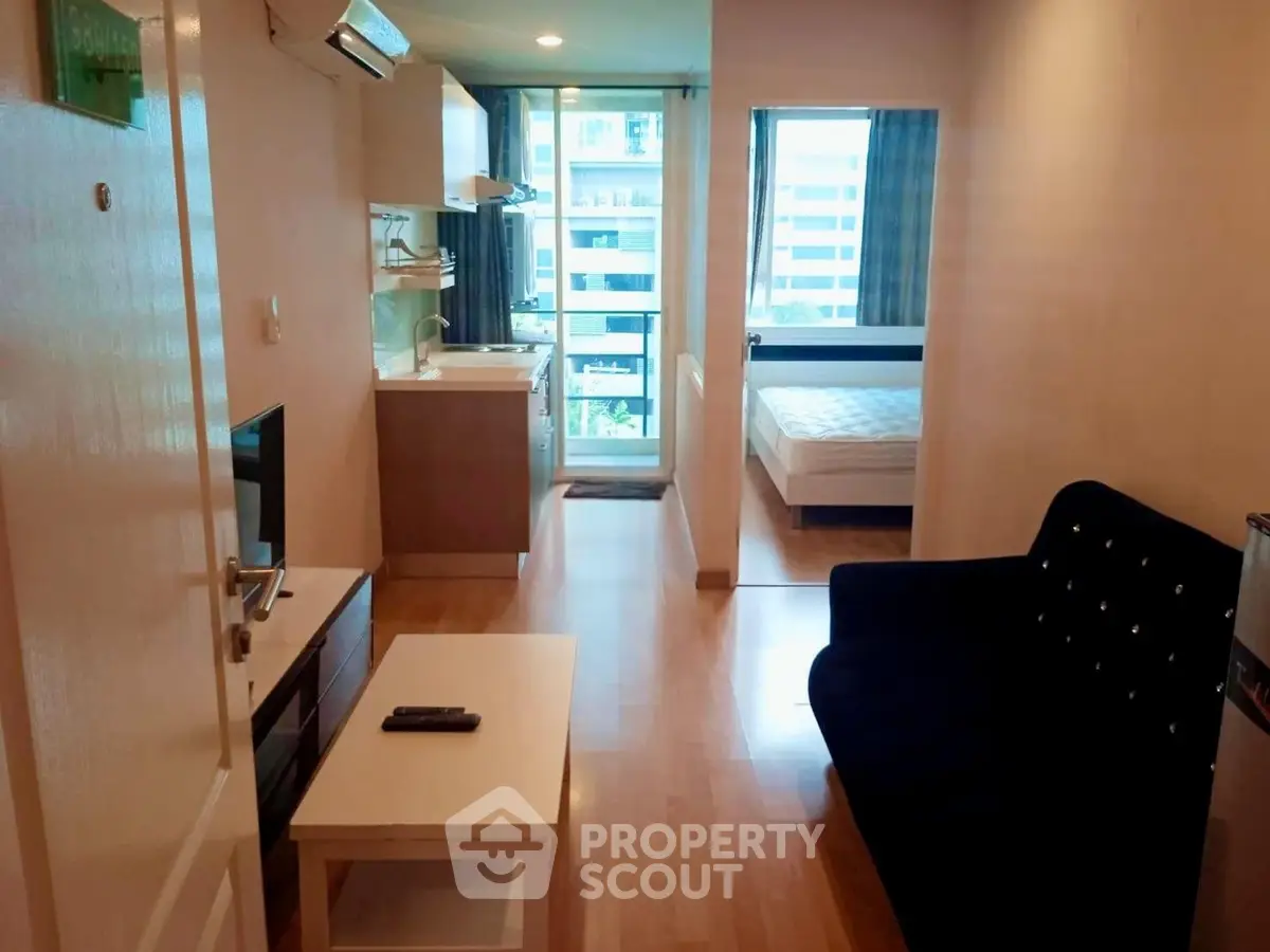 Modern apartment interior with open layout, featuring cozy living room and kitchen, leading to a bright bedroom.