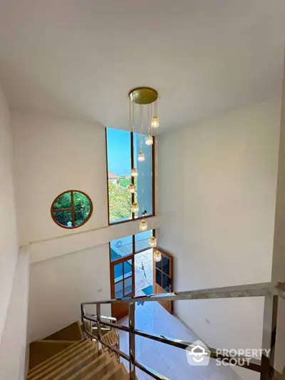 Elegant staircase with modern chandelier and large window view