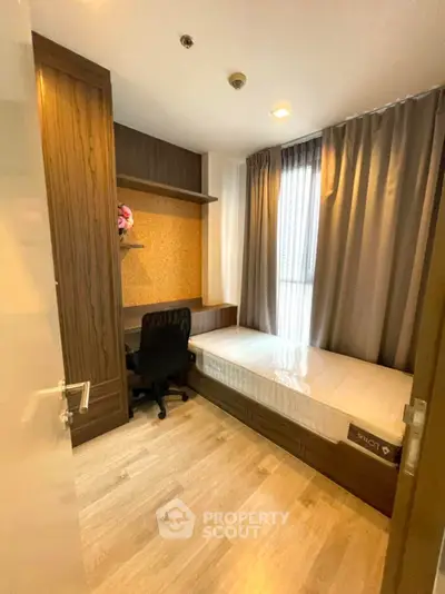 Cozy bedroom with wooden flooring, built-in wardrobe, and study desk in modern apartment.