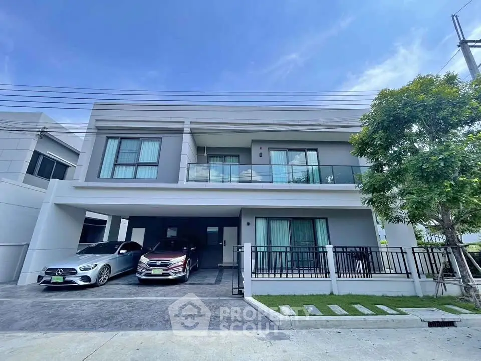Modern two-story house with spacious driveway and balcony, featuring sleek design and ample parking space.