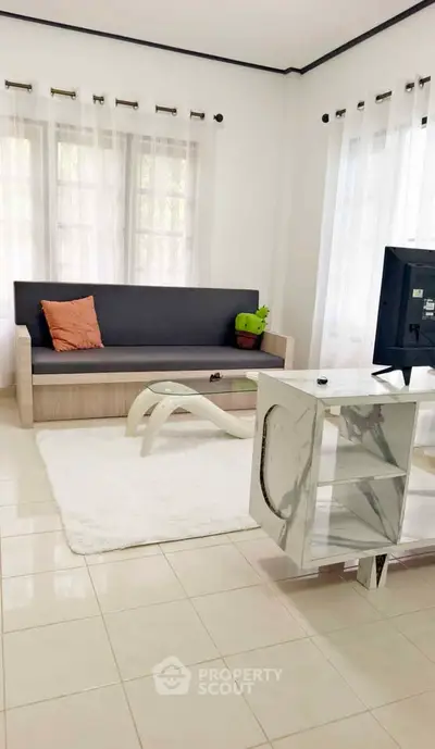 Bright living room with modern sofa and TV, featuring elegant decor and natural light.