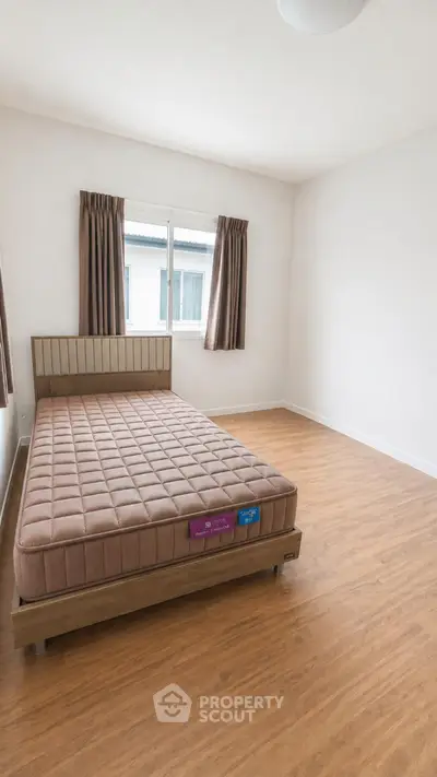 Spacious bedroom with wooden flooring and large window in modern apartment