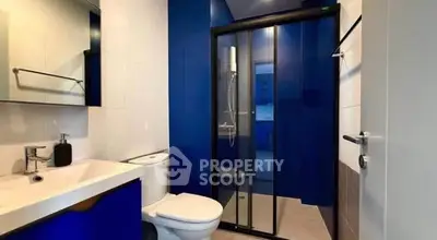 Modern bathroom with sleek blue accents and glass shower enclosure.