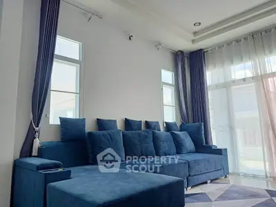 Spacious living room with modern blue sectional sofa and large windows for natural light.