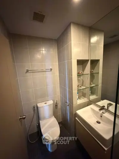 Modern bathroom with sleek fixtures and tiled walls, featuring a compact design.