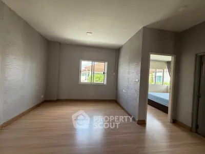 Spacious empty room with wooden flooring and natural light, ideal for customization.