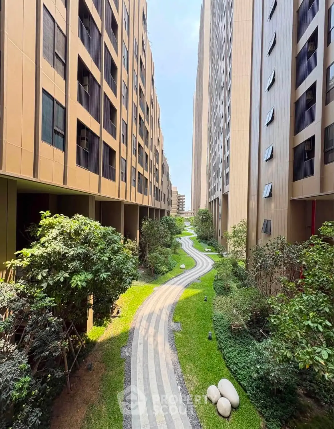 Modern residential building exterior with lush garden pathway and tall architecture.