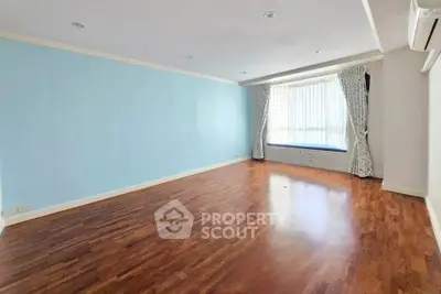 Spacious empty living room with hardwood floors and large window seat.