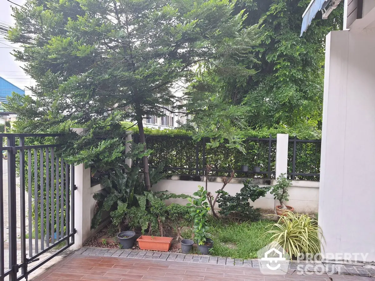 Charming private entrance with lush greenery and secure wrought iron gate, leading to a serene urban oasis.