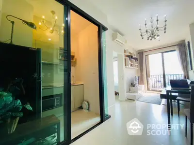 Modern open-plan living room with kitchen and balcony view, featuring elegant chandeliers and natural light.