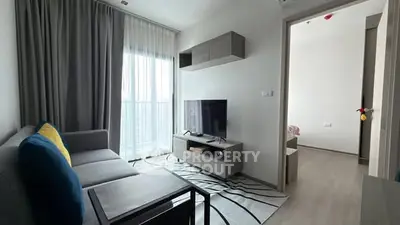 Modern living room with sleek furniture and large window offering natural light.