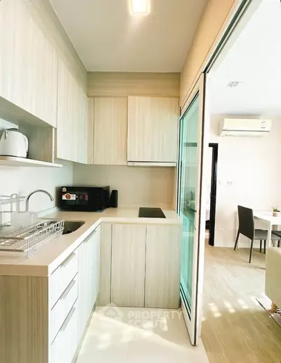 Modern kitchen with sleek cabinetry and open layout leading to dining area