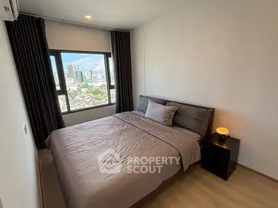 Modern bedroom with city view, featuring a cozy bed and stylish decor.